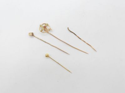 trois broches en or et une paire de boucles d'oreilles posées sur un fond blanc