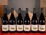six bottles of red wine are lined up on a table