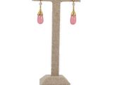 a pair of pink and gold earrings on a stand