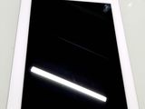 une tablette blanche posée sur une table, sur fond noir