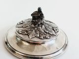 a silver plate with a flower on it on a white surface
