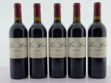 quatre bouteilles de vin rouge sont alignées sur une table