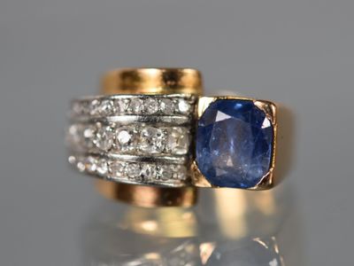un gros plan d'une bague en saphir et diamants posée sur une surface réfléchissante