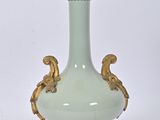 un vase vert et doré posé sur un socle et entouré d'une chaîne
