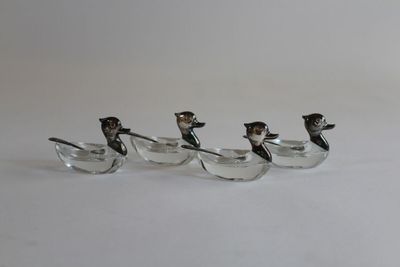 four glass ducks that are sitting in a row