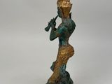 bronze statue of a woman playing a flute on a rock