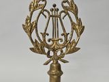 une image représentant une plaque en laiton ornée d'une harpe et de branches de laurier