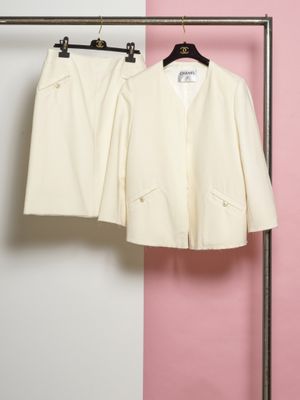 deux vêtements blancs suspendus à un portant devant un mur rose et blanc