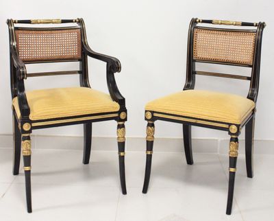une paire de chaises peintes en noir et or, avec un dossier en rotin