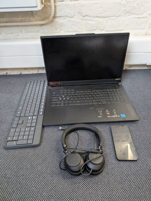 a laptop and headphones on the floor next to a remote