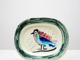 une petite assiette sur laquelle est représenté un oiseau, posée sur une table