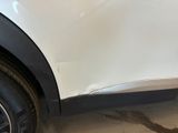 the side of a white car with a denting dent on it