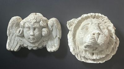 two white sculptures of a lion and a lion ' s head on a wall