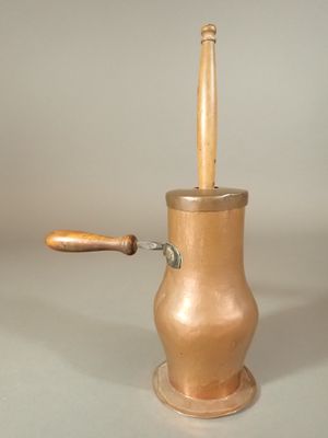 a small copper pot with a wooden handle sitting on a table