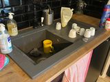 a sink in the middle of a kitchen with a lot of cleaning products