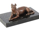 statue of a dog laying on a black marble base