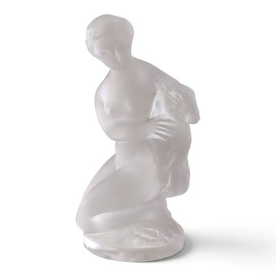 une statue blanche représentant une femme avec un sac sur le dos