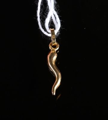 un pendentif en forme de serpent plaqué or, muni d'un cordon blanc, sur fond noir