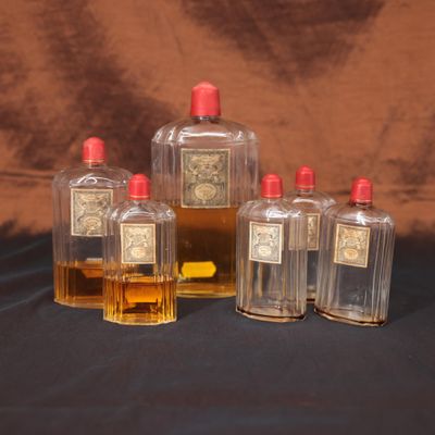 quatre flacons de parfum posés sur une table devant un fond marron