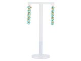 une paire de boucles d'oreilles turquoise et or posées sur un socle blanc