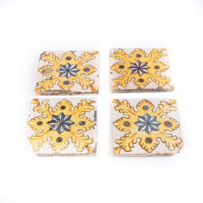quatre carreaux carrés ornés de motifs jaunes et bleus sur un fond blanc