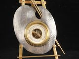 une image représentant une horloge en argent et en or posée sur un socle en bois