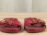 pair of red leather sandals with gold buckles on a wooden surface