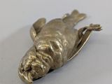 a metal object that looks like a frog on a white surface