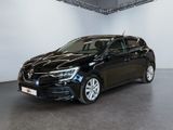 Une voiture noire est garée dans une grande pièce aux murs blancs.