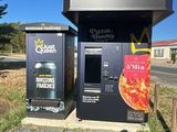 two vending machines sitting on the side of a road next to a parking lot