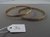 two gold bracelets on a table with a price tag