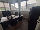 a desk with two computers and a refrigerator in the room