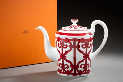 une théière rouge et blanche posée à côté d'une boîte orange
