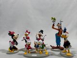 mickey mouse and friends figurines are posed on a white surface