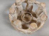 a small white vase with three figurines inside of it