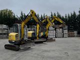 three excavators that are parked in a parking lot