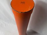 a small orange vase sitting on a white surface
