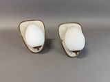 a pair of white glass and gold plated earrings on a gray surface