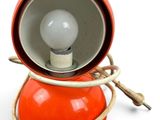 an orange lamp that is on top of a white table
