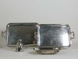 two silver trays with handles and handles on a white surface