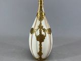 un vase blanc et doré orné d'une croix