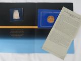 an open book with a picture of a coin and a piece of paper on it