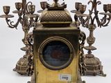 a clock that is sitting on a stand with candles
