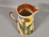 a small pitcher with a flower painted on it