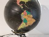 un globe noir orné d'une carte, posé sur un socle