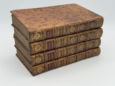 several old books stacked on top of each other on a white surface