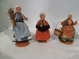 trois figurines représentant des femmes avec des paniers, posées sur une table