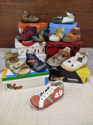 a pile of children ' s shoes and shoes on a bed