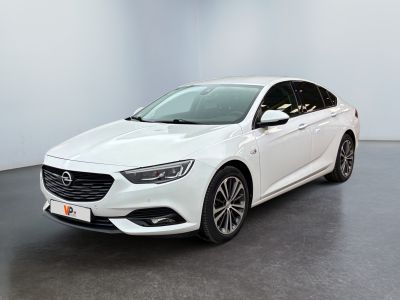 Une voiture blanche est garée dans une pièce blanche au sol noir.
