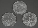 three coins are shown on a black surface with a white background